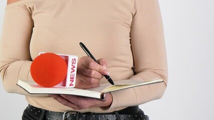 Close up of journalist holding microphone and writing.