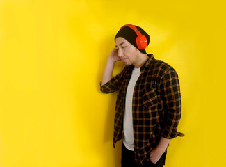 Side View Of Young Man Wear Beanie Hat And Casual Clothes Enjoying Listening Music From Headphones On Yellow Background With Copy Space