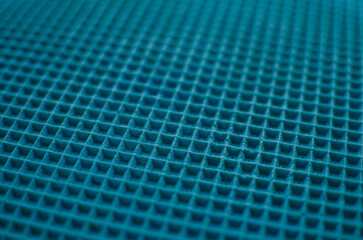 This is a close-up of a waffle-like texture in vibrant sky blue color, featuring a uniform grid of raised square cells with subtle shadows and a soft, tactile surface.