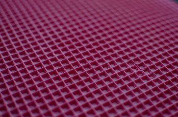This is a close-up of a waffle-like texture in vibrant magenta color, featuring a uniform grid of raised square cells with subtle shadows and a soft, tactile surface.