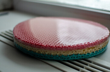 These are pre-packaged colorful waffle cake layers (ready-made sponge sheets) for assembling a layered cake, featuring a vibrant gradient of pink, beige, and turquoise, with a classic waffle texture, 