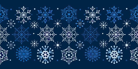 A seamless pattern of delicate ornate snowflakes on a dark blue background