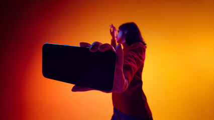 Smartphone with blank screen held by woman on gradient background. Concept of app mockup advertising, mobile interface promotion, digital product marketing, and tech layouts.