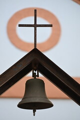 Jesus cross and a bell above the gate of a vintage chapel
