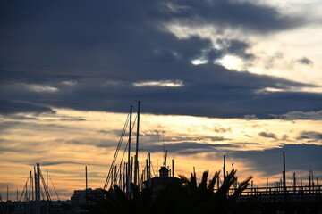 Sunset over marina with masts and red orange sky
