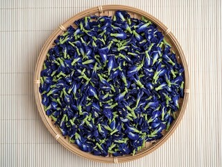 Dried butterfly pea flowers in a round bamboo basket