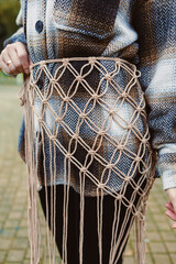 Creative macrame belt displayed by a fashionable individual in a park during a sunny autumn afternoon