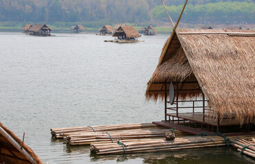 Tropical resort landscape featuring a wooden hut on the beach and a bungalow on the river with a boat near the summer sunset lagoon