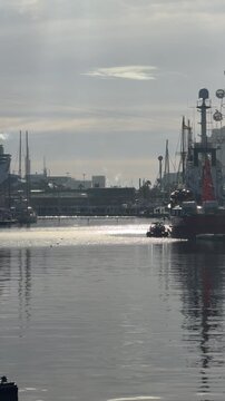 Sailboats and industrial port at Barcelona harbor with calm water reflections
