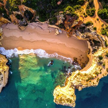 Top-down beach cove, cliffs, turquoise water, golden sand