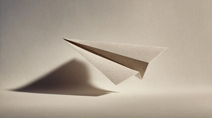 A simple paper airplane hovers above a textured surface, casting a soft shadow, symbolizing creativity and the joy of flight.