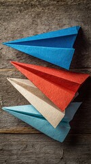 Colorful paper airplanes stacked on a wooden surface, showcasing creativity and playfulness in a simple and artistic arrangement.