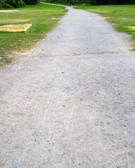 Obraz premium Scenic gravel path winding through green park area under overcast sky