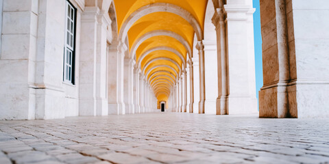 Long arched corridor featuring repeating columns and yellow vaulted ceiling creating deep perspective and sense of infinity