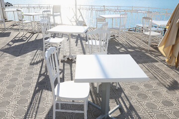 White furniture on terrace by sea on sunny day. Tourism and recreation, Europe. Nature and architecture of Italy. Design backdrop.