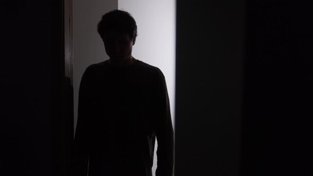 Social withdrawal and emotional exhaustion, man pausing in doorway and taking deep breath, avoiding going outside, stress overload, hesitation and retreat back into room