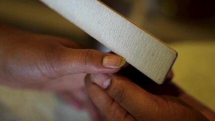 A manicurist carefully files a client's nails by hand during a detailed nail care session