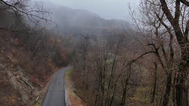 Fog rolling over forested hills in Castelletto Val Tolla, Emilia Romagna, Italy painting a mysterious and tranquil autumn winter scene with a thick blanket of haze, near Mignano dam lake