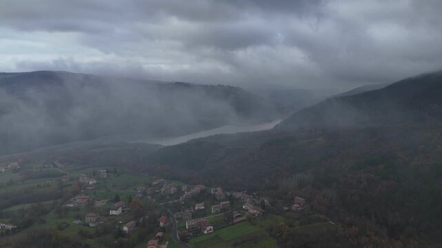 Fog rolling over forested hills in Castelletto Val Tolla, Emilia Romagna, Italy painting a mysterious and tranquil autumn winter scene with a thick blanket of haze, near Mignano dam lake