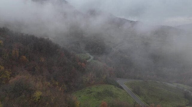 Fog rolling over forested hills in Castelletto Val Tolla, Emilia Romagna, Italy painting a mysterious and tranquil autumn winter scene with a thick blanket of haze, near Mignano dam lake