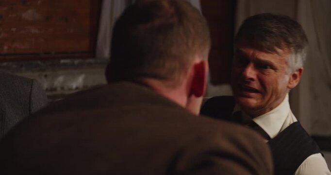 Prohibition era concept - a scared man wearing a business suit gets interrogated and begs for his life