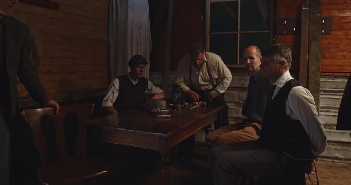 Prohibition era concept - A tied man wearing a business suit is tied up in a gangster hideout and is being interrogated