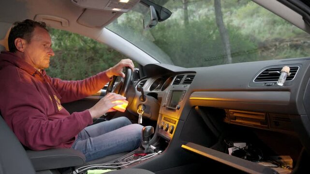 A man with a broken-down car on the roadside is taking out the new V16 emergency light beacon from the glove box and placing it on the roof