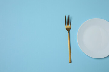 Empty plate and cutlery on colored background, top view
