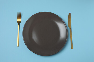 Empty plate and cutlery on colored background, top view
