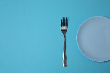 Empty plate and cutlery on colored background, top view
