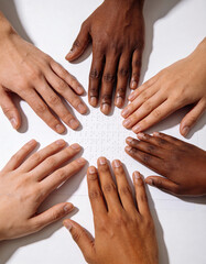 Hands of diverse skin tones reading Braille together on a clean background, symbolizing diversity, inclusion, accessibility, literacy, and collaborative learning for social awareness campaigns