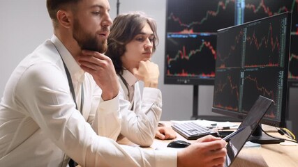 Focused at work, analyzing the data. Two male exchange workers are in the office together - Powered by Adobe