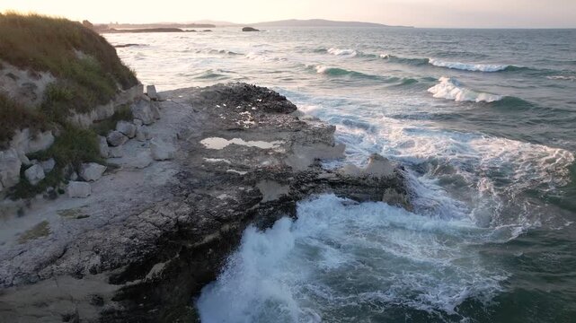 Aerial view of waves crashing against a rocky coastline, creating a dynamic interplay of white foam and dark rock textures, Lozenets, Tsarevo, Bulgaria.