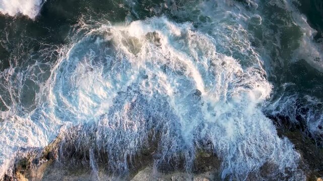 Aerial view of the rugged, rocky coastline where the dark rocks meet the white foamy waves of the sea, creating a dynamic contrast of textures, Lozenets, Tsarevo, Bulgaria.