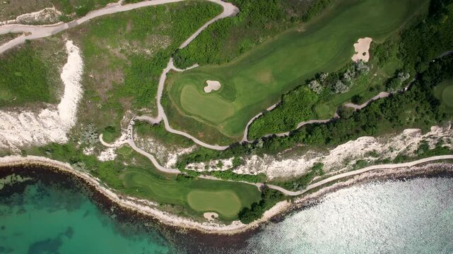 Aerial view of the vibrant green golf course contrasting with the turquoise sea and sandy bunkers, winding paths, Bozhurets, Kavarna, Bulgaria.