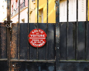 Sortie de voiture. Pri&egrave;re de ne pas stationner.  Panneau rond blanc et rouge d'interdiction de stationner sur une palissade en bois. 