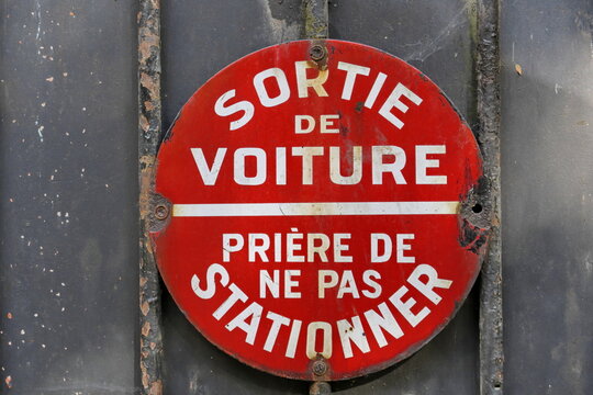 Sortie de voiture. Pri&egrave;re de ne pas stationner.  Panneau rond blanc et rouge d'interdiction de stationner sur une palissade en bois. 