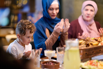 Fototapeta premium Muslim family sharing iftar in a restaurant decorated for Ramadan celebrations