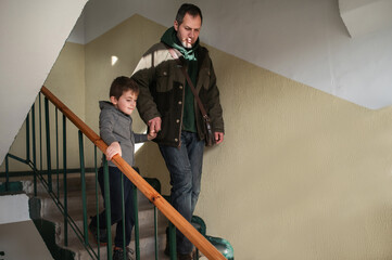 A father and his preschool-aged son walk down the stairs of their apartment building, their morning routine of getting ready for kindergarten.