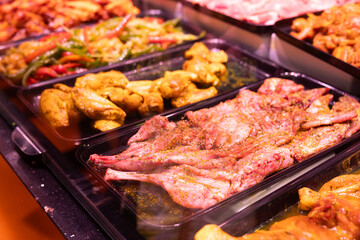 Raw skinned marinated rabbit quarters and halves in refrigerator cabinet of butcher shop.