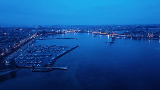 Aerial view of the marina with numerous boats docked, contrasted against the city lights along the shoreline, Rade of Geneva, Geneva, Switzerland.