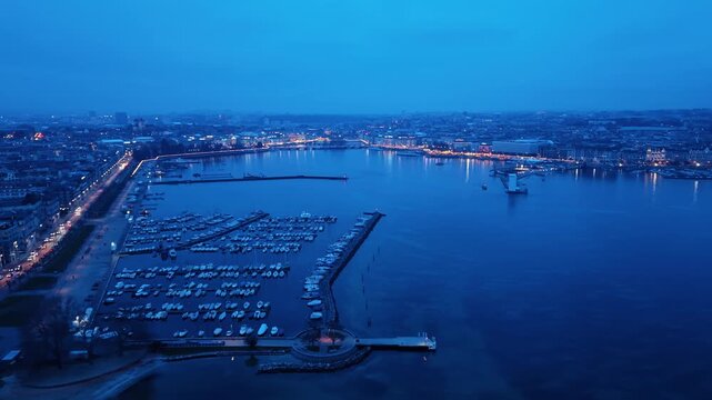 Aerial view of the harbor filled with boats, contrasted by the city lights along the coastline, creating a captivating scene, Rade of Geneva, Geneva, Switzerland.