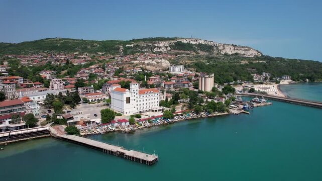 Aerial view of the vibrant coastal city featuring a striking white building against the backdrop of a cliff, overlooking boats in the turquoise sea, Balchik, Dobrich Province, Bulgaria.