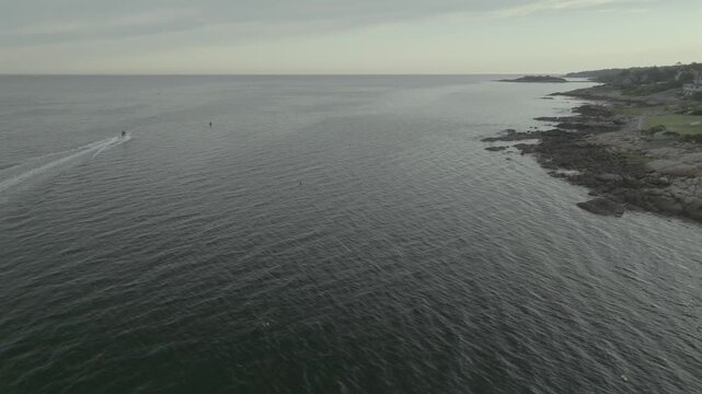 Aerial view of the rugged Gloucester coastline meeting the calm ocean under a soft, muted sky, Gloucester, Massachusetts, United States.