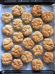 directly above shot of fresh baked healthy oatmeal cookies on baking tray with parchment paper 