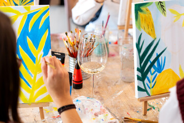 Women painting tropical scene during sip and paint event