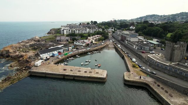 Aerial view of Dalkey Harbour, where boats rest on the calm water, contrasting with the bustling streets and buildings, Dalkey, County Dublin, Ireland.