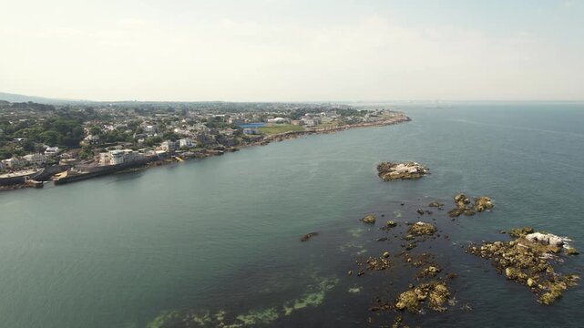 Aerial view of the Dalkey coastline and ocean, where the town's buildings meet the water, creating a scenic contrast against the rocky coastline, Dalkey, County Dublin, Ireland.