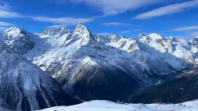 View of Dombay glaciers and mountain peaks in the winter sun. Panorama of the snow-capped Caucasus Mountains in sunny weather. Dombay-Ulgen and Moussa-Achitara mountains. Ski resort in Russia.