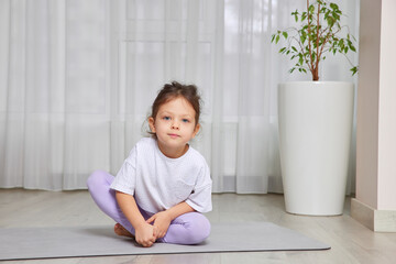 Young girl practices wellness, sitting on a yoga mat in a bright room